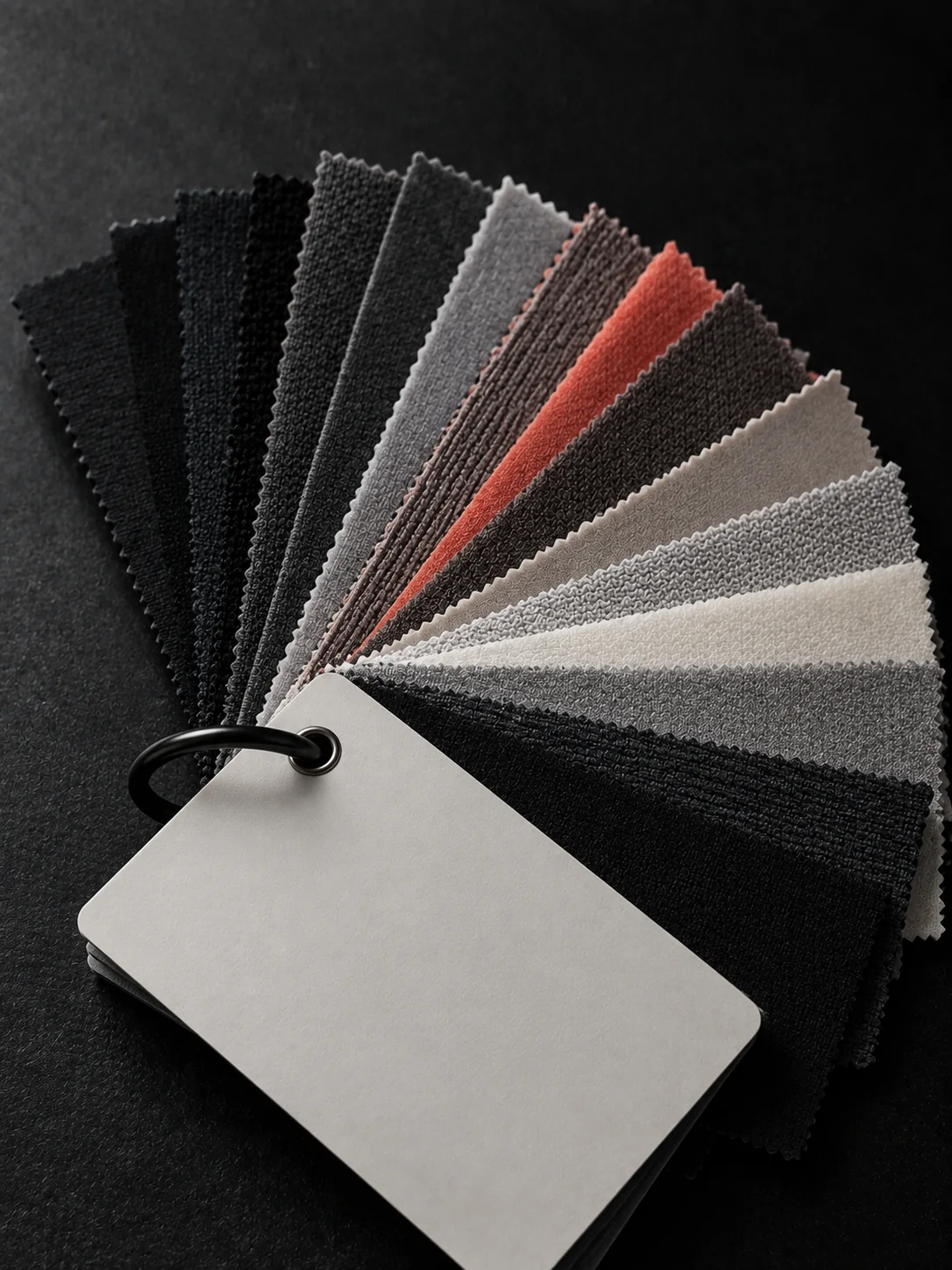 Fan of fabric swatches in black, greys and coral on a ring